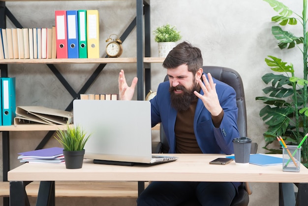 Wpadłem w bałagan. Mężczyzna Brodaty szef szef siedzieć biuro z laptopem. Menedżer rozwiązujący problemy biznesowe online. Biznesmen nie powiódł się. Ryzykowny biznes. Broker i wskaźniki finansowe. Spadające ceny akcji.