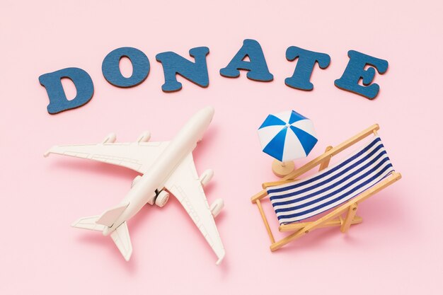 Wpłać parasol plażowy z zabawkami słownymi i leżak na różowym tle koncepcji na temat darowizny na wakacje