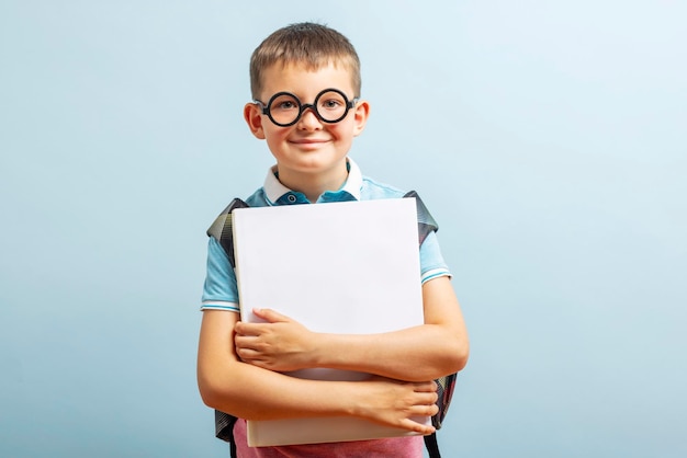 Wróć do szkoły szczęśliwy uczeń szkoły podstawowej w okularach uściska książkę
