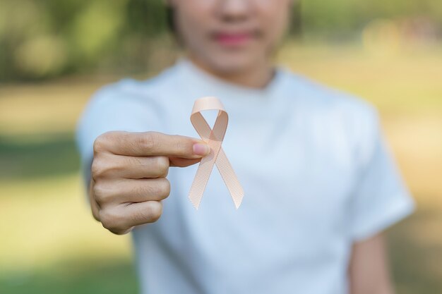 Zdjęcie wrzesień miesiąc świadomości raka macicy, kobieta trzymająca za rękę brzoskwiniową wstążkę do wspierania ludzi żyjących i chorych. koncepcja opieki zdrowotnej i światowego dnia raka