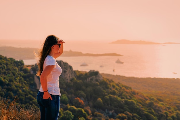 Wschód lub zachód słońca i młoda dama w Porto Rotondo w Costa Smeralda na Morzu Śródziemnym na wyspie Sardynii we Włoszech. Latem łódź na Sardynii.