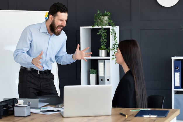 Wściekły biznesmen krzyczeć na pracownicę pracującą we wspólnym biurze