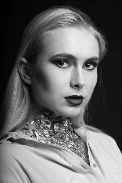 Wspaniała Blond Modelka Pozuje W Studio Z Jasnym Makijażem I Folią Na Szyi. Strzał Monochromatyczny