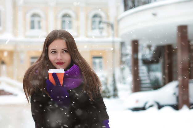 Wspaniała brunetka kobieta z długimi włosami picia grzanego wina w śnieżny dzień. Miejsce na tekst