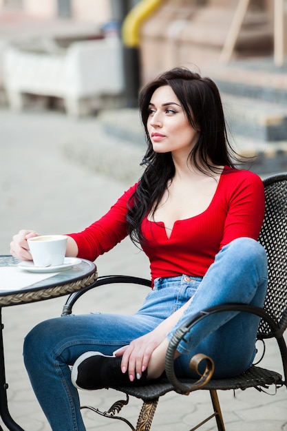 Wspaniała młoda kobieta z filiżanką kawy na ulicy miasta