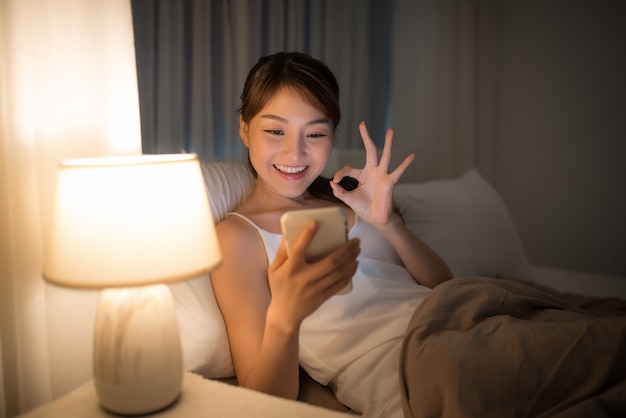 Wspaniała szczęśliwa kobieta w białym łóżku w domu z telefonem robi selfie