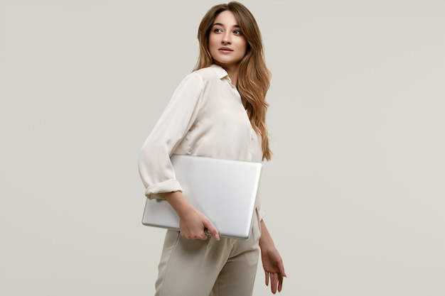 Wspaniałej brunetki wzorcowy pozować w biel ubraniach z laptopem