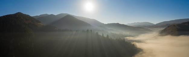 Wspaniały Górski Krajobraz. świt W Jesiennych Karpatach, Promienie Słoneczne Oświetlające Mgłę I żółte Jesienne Drzewa. Widok Z Drona.