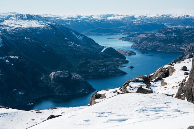 Wspaniały krajobraz jeziora kanał morza między skalistym brzegiem ze śniegiem Most w tle Górny widok na Pulpit Rock Preikestolen norweskie góry Lysefjord Norwegia