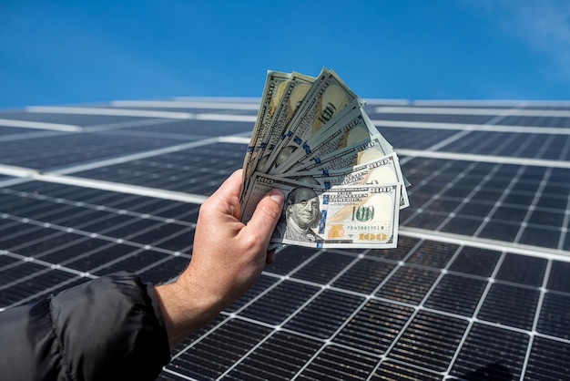 Wspaniały robotnik trzyma w rękach kwotę pieniędzy na instalację paneli słonecznych