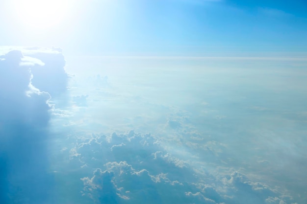 Wspaniały widok z okna samolotu w porannym słońcu nad chmurami Niezwykłe chmury oświetlone promieniami słońca Białe chmury na tle błękitnego nieba Płonące słońce i niebo Panorama nieba