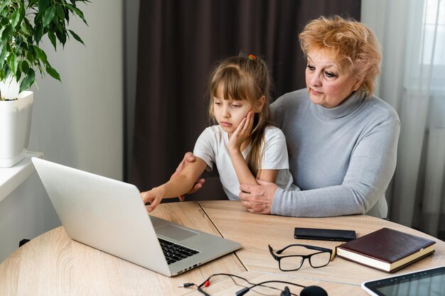 współczesna babcia uczy wnuka obsługi laptopa w domu