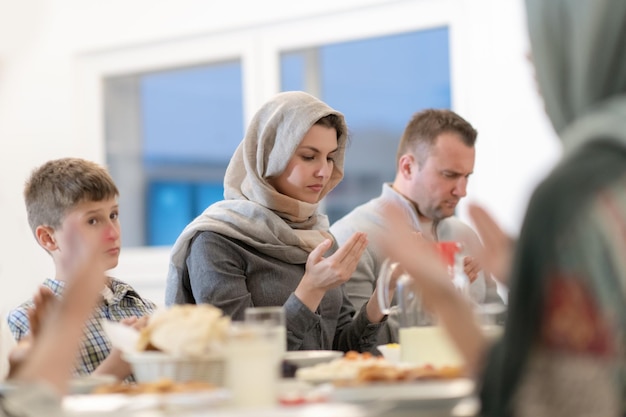 współczesna muzułmańska rodzina modli się przed wspólną kolacją iftar podczas uczty ramadanu w domu