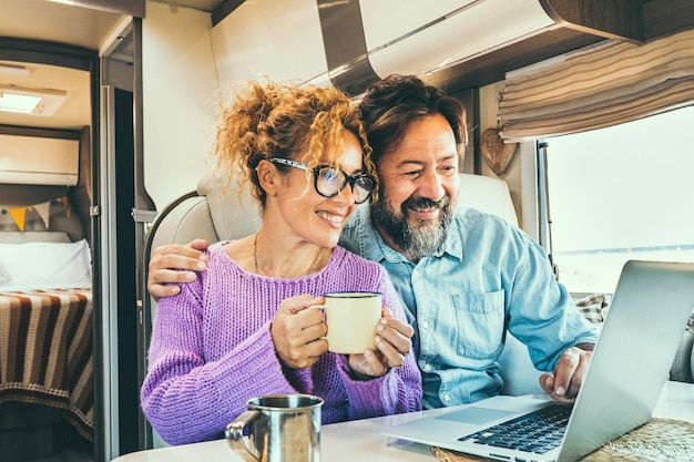 Zdjęcie współczesna para używa razem laptopa w przyczepie komputerowej ludzie spędzający wolny czas surfujący w internecie podróżujący planujący następny cel uśmiechający się i cieszący się wolnością żyjący poza siecią koncepcja cyfrowego nomada