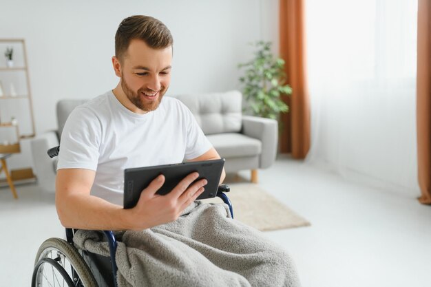 Współczesny młody niepełnosprawny mężczyzna na wózku inwalidzkim podczas rozmowy wideo