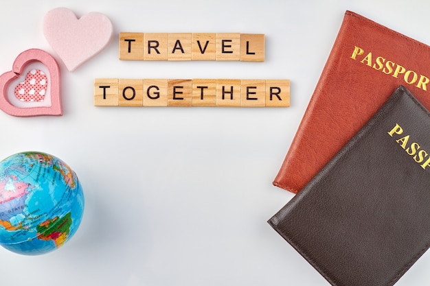Wspólne podróżowanie jest bardzo romantyczne. Paszporty i różowe serca z kulą ziemską na białym tle.