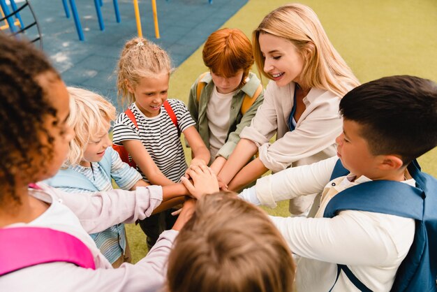 Współpraca w małej grupie uczniów Duch zespołowy w szkole między uczniami Młodzi uczniowie mieszanych ras stojący razem w okrągłym pierścieniu