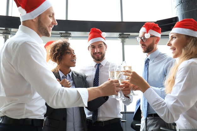 Współpracownicy biurowi wspólnie świętują ferie zimowe w pracy i piją szampana w biurze. Wesołych Świąt i Szczęśliwego Nowego Roku.
