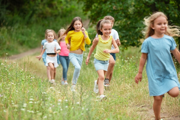 Wspomnienia. Dzieciaki, dzieci biegające po zielonym lesie. Wesołych i szczęśliwych chłopców i dziewcząt bawiących się, śmiejących się, biegających po zielonej kwitnącej łące. Dzieciństwo i lato, koncepcja szczere emocje.