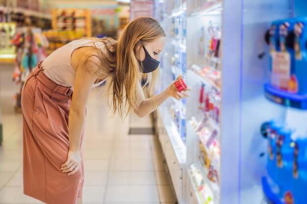 Wstrząśnięta kobieta nosi maskę medyczną przeciwko koronawirusowi podczas zakupu chemikaliów domowych w