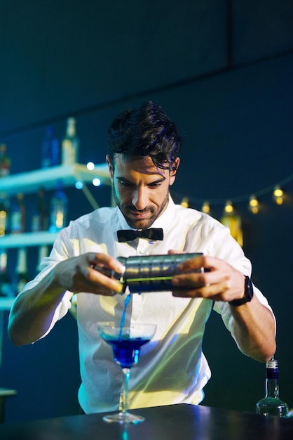 Wstrząśnięty mieszany podany Ujęcie przystojnego młodego barmana nalewającego koktajl do szklanki w nocnym klubie