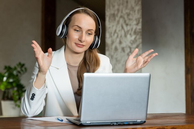 Zdjęcie wszystkiego najlepszego z okazji czarująca młoda kobieta biznesu ubrana w zestaw słuchawkowy ma rozmowę wideo na laptopie młoda kobieta w biurze
