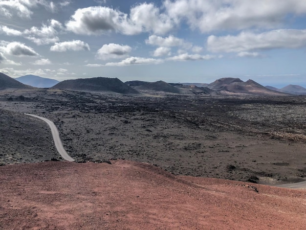 Zdjęcie wulkaniczny krajobraz i droga w parku narodowym timanfaya z wulkanami i górami na lanzarote