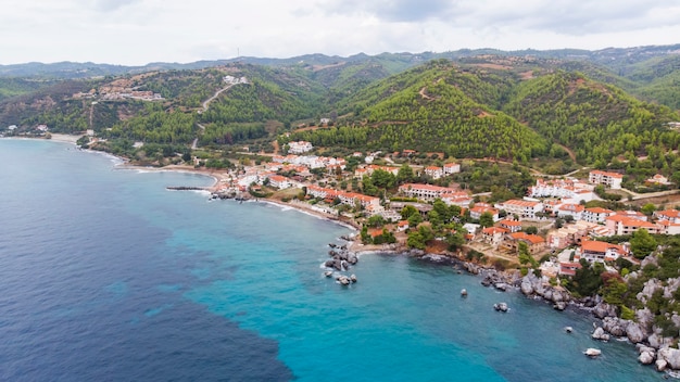 Wybrzeże Morza Egejskiego Grecji, budynki Loutra położone w pobliżu skalistych klifów, zieleni i błękitnej wody. Widok z drona