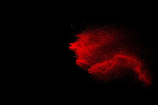 Wybuch czerwone cząsteczki na czarnym tle. Zablokuj ruch rozpylania czerwonego pyłu