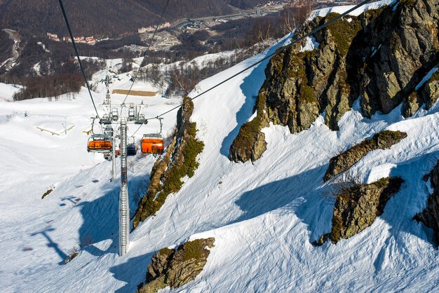 Wyciąg krzesełkowy w górach w zimie wyciąga turystów, narciarzy i snowboardzistów na stok