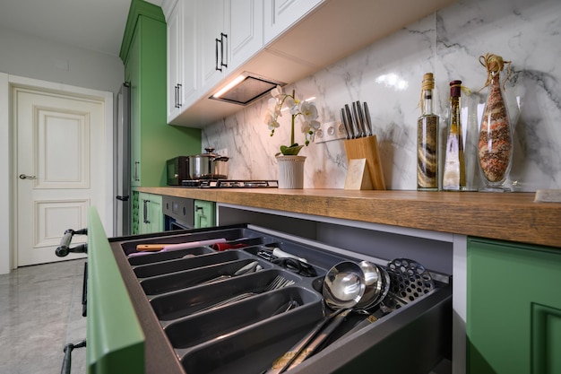 Zdjęcie wyciągnięta szuflada z przyborami kuchennymi w nowej zielonej kuchni