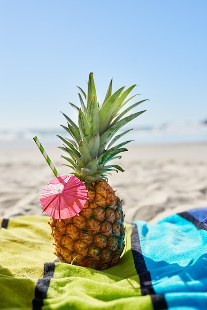 Wycieczka koktajlowa i zbliżenie ananasu na plaży z alkoholem na ręczniku na wakacje Letni ocean i tropikalne owoce organiczne z słomką lub papierowym parasolem na piasku na wakacje nad morzem