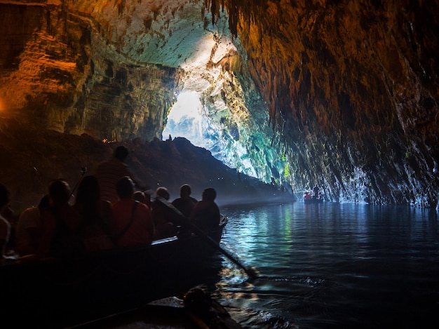 Wycieczka przez turystów łodzią w jaskini z podziemnym jeziorem Melissani na wyspie Kefalonia w Grecji