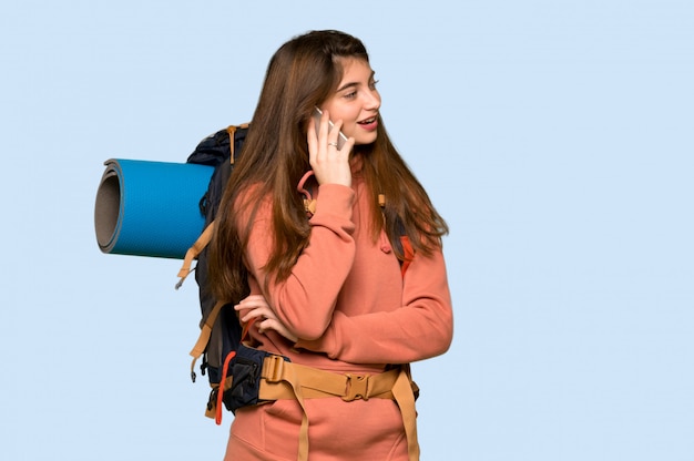Wycieczkowicz dziewczyna utrzymuje rozmowę z telefonem komórkowym na błękicie