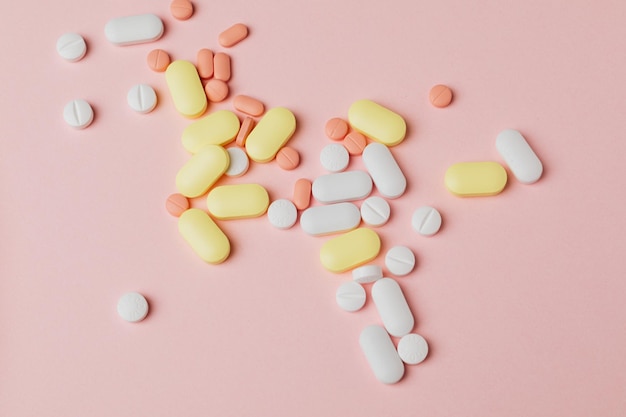Wyciekająca butelka pigułki. kolorowe tabletki kapsułki na powierzchni tabletek na różowym tle