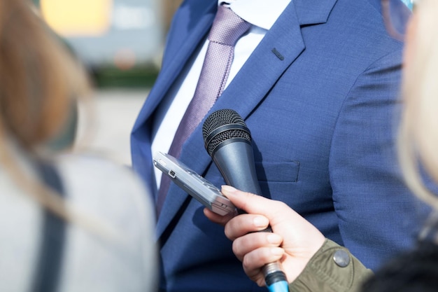 Zdjęcie wycięte zdjęcie dziennikarza trzymającego mikrofony i telefon komórkowy przez biznesmena