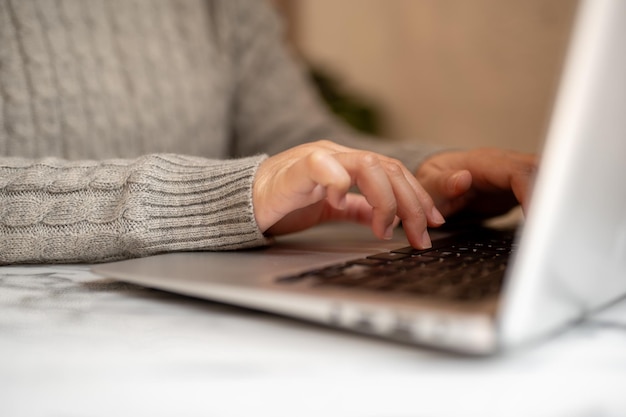 Wycięte zdjęcie kobiety pracującej na swoim laptopie pisząc na klawiaturze laptopa