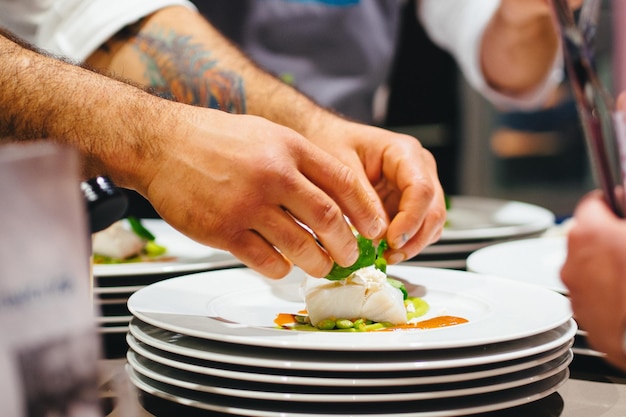 Wycięty obraz szefa kuchni przygotowującego owoce morza na talerzu w restauracji