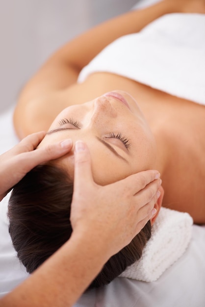 Wycofywanie się w miejsce spokojnego relaksu Młoda kobieta leżąca w spa, otrzymująca relaksujący masaż głowy