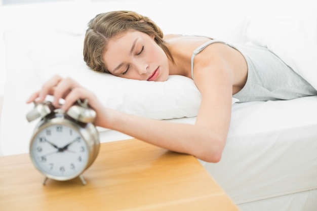 Wyczerpana młoda kobieta wyłączyć budzik