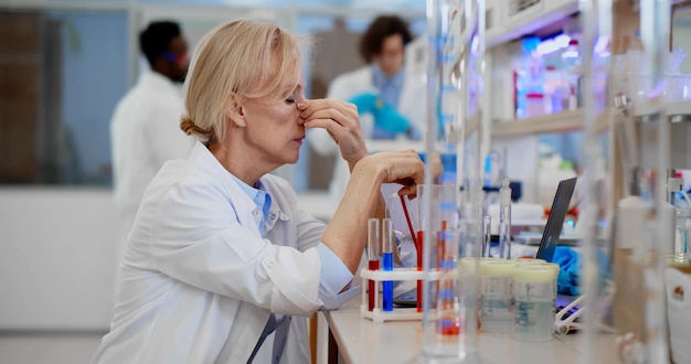 Wyczerpany naukowiec siedzi przy biurku w laboratorium chemicznym