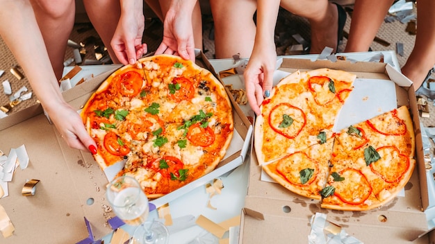 Wydarzenie specjalne Usługa dostawy fast foodów Przycięte zdjęcie kobiet jedzących pyszną pizzę na ich fantazyjnym przyjęciu