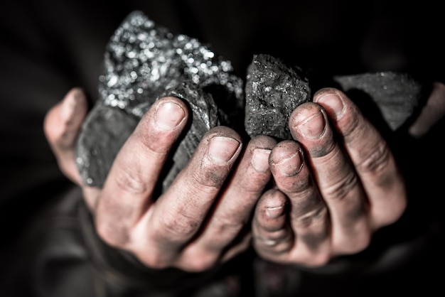 Wydobycie węgla górnik w rękach człowieka tle węgla. Pomysł na zdjęcie o wydobyciu węgla lub ener