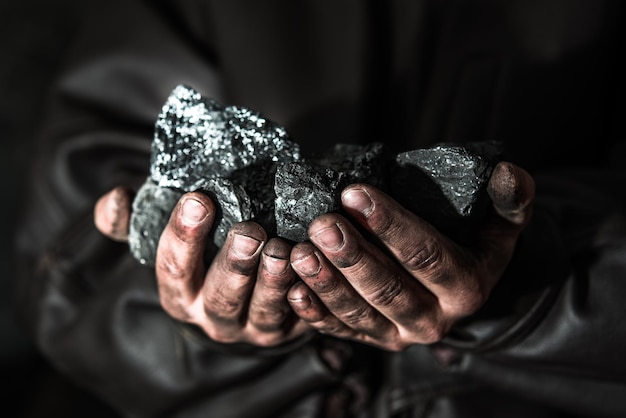 Wydobycie węgla górnik w rękach człowieka tle węgla. Pomysł na zdjęcie o wydobyciu węgla lub ener