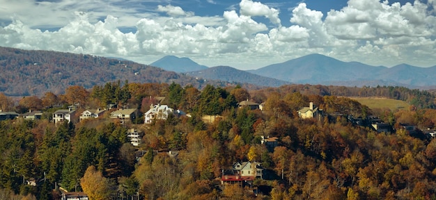 Wygląd z góry drogich domów mieszkalnych wysoko na szczycie wzgórza między żółtymi drzewami jesieni w przedmieściach Północnej Karoliny Amerykańskie domy marzeń jako przykład rozwoju nieruchomości na przedmieściach Stanów Zjednoczonych