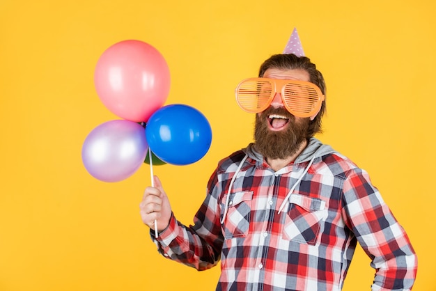Wyglądający dobrze zabawny mężczyzna w urodzinowym kapeluszu szczęśliwe wakacje celebrujący imprezę szalony bawiący się balonami przygotowujący się na rocznicę najlepszy menedżer imprez brutalny mężczyzna na imprezie