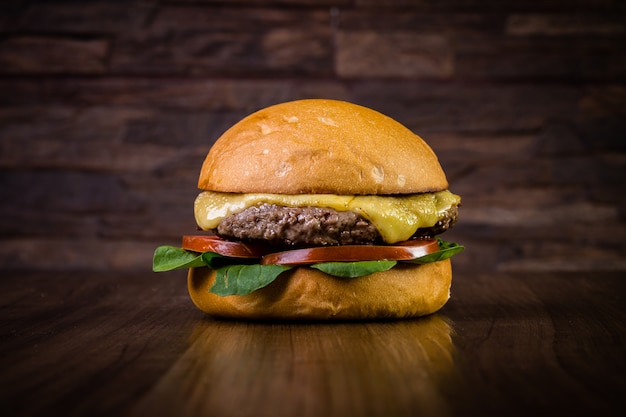 Wykonaj burger wołowy z liśćmi sera i rukoli na drewnianym stole