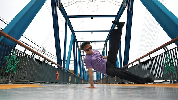 Wykwalifikowani hipsterzy wykonują bboy footstep i break dance na moście.