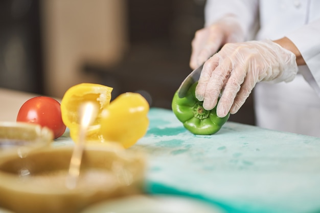 Wykwalifikowany szef kuchni kroi świeżą soczystą zieloną paprykę