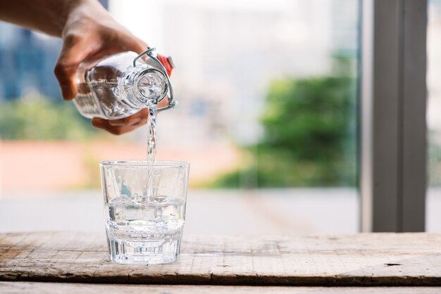 Wylewanie oczyszczonej świeżej wody pitnej z butelki na stół w salonie